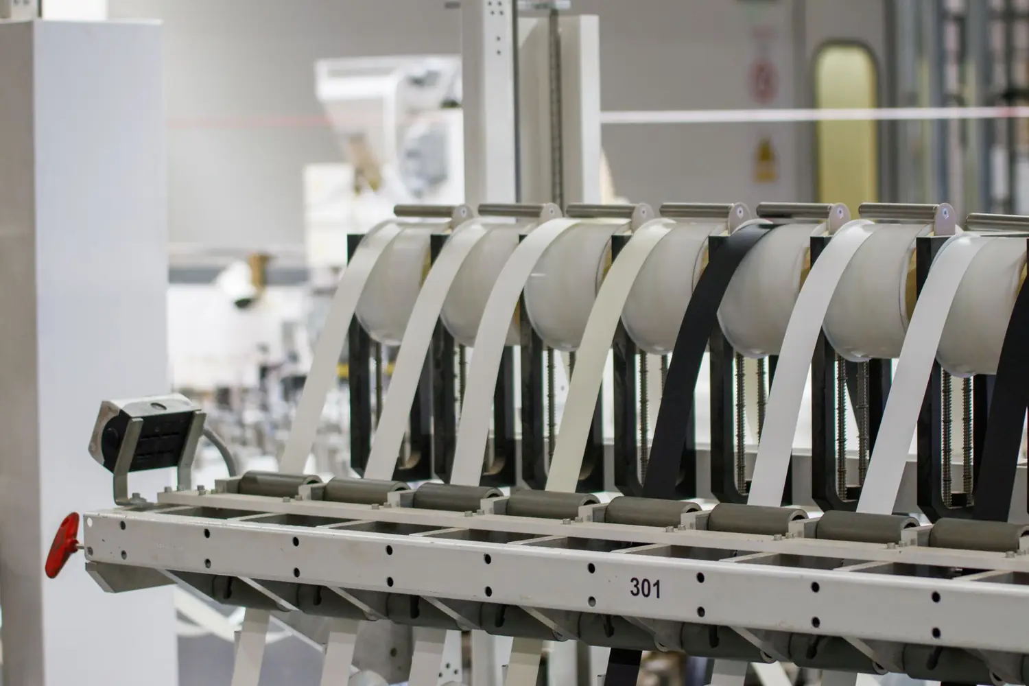Row of guide rollers carrying material webs on a converting line